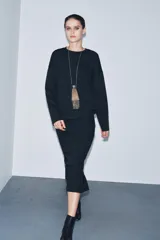 Falda midi de tiro medio confeccionada en tejido soft, con cintura elástica y abertura en la parte posterior.