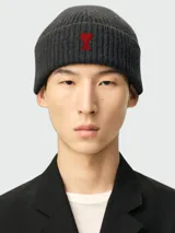 Gorro de lana gris oscuro tejido en canalé, con vuelta y bordado frontal en forma de corazón rojo con la letra A de la marca Ami Paris.