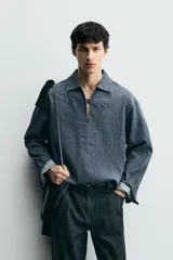 Sobrecamisa de algodón con lavado oscuro, cuello solapa y abertura frontal con cierre. Presenta un calce relajado y mangas largas.