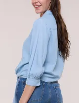 Camisa de lyocell color celeste, con cuello camisero, cierre frontal con botones y detalle de nudo en el ruedo. Presenta mangas tres cuartos abullonadas con puños elásticos.