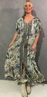 Vestido largo de seda con estampado paisley en tonos azules, celestes y crudo, escote en V con cordón y borlas, y mangas cortas fluidas con volados.