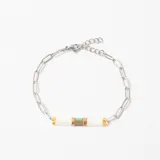 Pulsera de cadena de eslabones plateados con detalle central compuesto por cuentas rectangulares blancas, doradas y una pieza central con tonos turquesa y bronce.