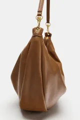 Bolso de hombro de diseño slouchy en color marrón, con asa de hombro ajustable mediante mosquetones metálicos dorados y cierre superior de cremallera.