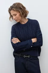 Sweater de punto trenzado en color azul marino, con cuello redondo y mangas largas. Presenta un diseño de tejido con textura en el frente y mangas lisas.