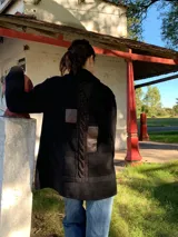 Saco negro de lana con cierre de broches tipo duffle coat, bolsillos laterales con solapa de cuero y detalle de trenza en la espalda.