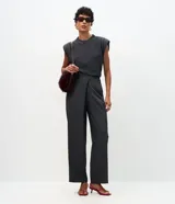 Pantalón de sastrería color gris oscuro, de tiro alto y corte recto. Presenta un diseño sofisticado con un cruce frontal superpuesto en la cintura y cierre oculto.