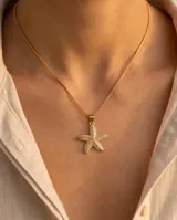 Collar de cadena fina eslabonada en color dorado con dije en forma de estrella de mar, cubierto de circones brillantes.