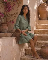 Vestido corto verde militar de lino, con cuello mao, escote en V con botones, mangas tres cuartos acampanadas con volados y falda con volado en el ruedo.