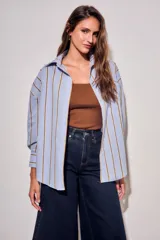 Camisa de corte oversize con estampado de rayas verticales en tonos azul claro y mostaza. Presenta cuello clásico, cierre frontal con botones y mangas largas con puños abotonados.