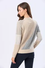 Buzo tejido de punto con diseño de bloques de color en diagonal en tonos beige, gris y rosado. Presenta cuello redondo, manga larga y terminaciones acanaladas en cuello, puños y cintura.