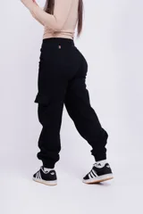 Pantalón mom cargo de jean negro con bolsillos laterales y tobillos ajustados.