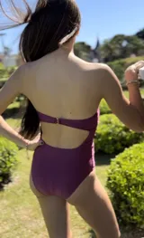 Malla enteriza strapless color bordó con acabado satinado y corte de pierna alto.