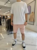 Bermuda de jogging color beige, con bolsillos laterales y estampa con texto blanco en la pierna izquierda.