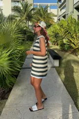 Vestido corto tejido a rayas horizontales en verde oscuro y beige, con cuello redondo y ribete celeste en el cuello y el dobladillo.