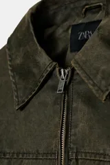 Chaqueta encerada color verde militar, con cuello solapa, manga larga, bolsillos de vivo en el delantero y bajo acabado en elástico. Cierre frontal con cremallera.