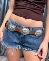 Cinturón de cuero sintético color marrón con apliques metálicos circulares grabados en tono plateado.