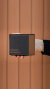 Billetera de hombre en cuero color negro y marrón, con solapa superior y monedero con tapa y broche. Cuenta con espacio para billetes y reparticiones para tarjetas.