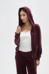 Campera con capucha de terciopelo color bordó, con cierre frontal, bolsillos tipo canguro y texto bordado en el pecho.