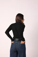 Polera blanca de cuello alto y mangas largas, de tejido acanalado.