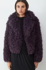 Campera corta de pelo sintético con textura rizada y voluminosa, de corte holgado y diseño envolvente.
