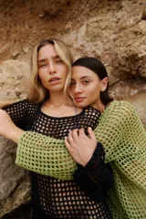 Vestido corto de tejido crochet calado en color negro, con mangas largas y diseño de espalda descubierta con cierre de lazo ajustable en el cuello.