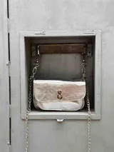 Minibag de diseño estructurado tipo acordeón, con acabado texturizado brillante en color negro. Cuenta con solapa frontal, cierre metálico giratorio y doble correa.