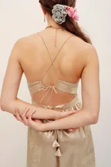 Vestido largo dorado de poliéster metalizado con tirantes finos, escote en V y corte fluido.