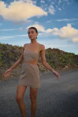 Vestido corto color gris, confeccionado en lino y rayón, con escote recto, breteles regulables y espalda con tiras regulables.