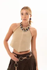 Top de gamuza color visón con escote halter y costuras decorativas con detalle de tientos de cuero en los bordes laterales.