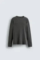 Camiseta de manga larga con cuello redondo, confeccionada en tejido de algodón con textura tipo waffle. Presenta un corte relajado, puños acanalados y un acabado con efecto lavado.