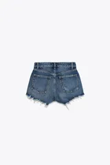 Short de jean negro desgastado, tiro alto, con roturas pronunciadas y terminación deshilachada en el bajo. Presenta cinco bolsillos y cierre frontal con botón metálico.