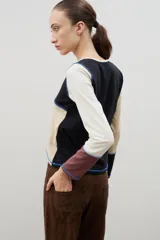 Remera de manga larga con diseño de bloques de color en tonos neutros, confeccionada con costuras externas visibles en color azul contrastante.