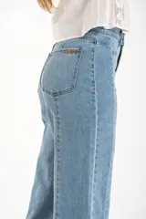 Jean de corte recto y tiro medio, confeccionado en denim de algodón con un toque de elastano. Presenta costuras verticales decorativas a lo largo de las piernas y un ruedo deshilachado.