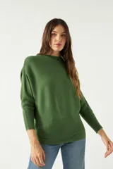 Sweater verde de punto liviano con textura acanalada y diseño de hombros caídos.