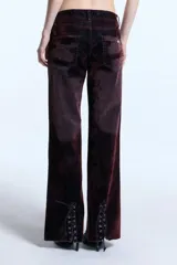 Jean de tiro bajo con corte flare, confeccionado en denim de algodón con un acabado efecto terciopelo. Presenta un lavado localizado que resalta la textura y cuenta con un detalle de ojalillos y cordón en la parte trasera de la botamanga.