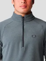 Buzo polar Mountain Hardwear modelo Microchill 1/4 Zip, color gris, con cuello alto, cierre frontal parcial de un cuarto y mangas raglán. Presenta detalles en color negro en los bordes del cuello, puños y ruedo, además de un pequeño logo bordado en el pecho.