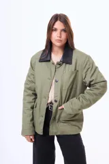 Campera de gabardina color verde militar con cuello de cuero sintético negro, cierre frontal con botones metálicos y bolsillos frontales con solapa.