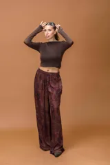 Pantalón palazzo de tiro medio con cintura elástica y cordón ajustable. Presenta un diseño de corte amplio y fluido con un estampado de motivos paisley en tonos marrones y azul oscuro.