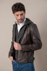 Campera marrón de cuero con capucha desmontable gris de felpa, cierre frontal y bolsillos con cierre, de corte clásico.