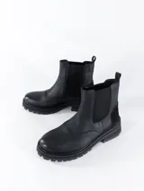 Bota Chelsea de cuero negro con elásticos laterales, suela track y tirador trasero.