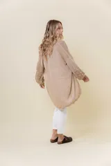 Cardigan tejido liviano color beige con efecto brillante y calados en las mangas. Diseño abierto y corte relajado.