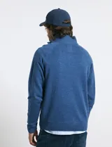 Sweater de punto color azul marino, con cuello alto, cierre frontal parcial y tapeta con botones. Presenta mangas raglán y puños y ruedo acanalados.