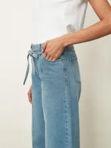 Jean de corte wide leg en color negro, con cintura alta ajustable mediante lazo y costuras verticales decorativas en el frente.