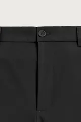Pantalón regular fit color negro de corte recto, con cintura elástica en los laterales, trabillas, bolsillos frontales y cierre con botón y cremallera.