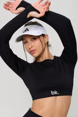 Conjunto deportivo compuesto por un top de manga larga con cuello redondo y calzas de tiro alto, ambos en color negro con detalles de textura en tejido seamless.