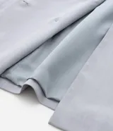 Blazer de corte sastrero color gris claro, con solapas, abotonado doble, forro interno y bolsillos frontales decorativos con solapa.