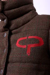 Campera corta con estampado abstracto en tonos marrones y beige, cuello alto, cierre frontal con botones a presión, bolsillos delanteros y bordado negro con las iniciales CP. Forro interior y relleno liviano de guata.