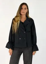 Chaqueta negra de estilo blazer con cierre frontal de doble botonadura, cuello solapa y mangas largas con puños acampanados y fruncidos.