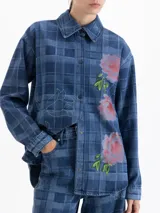 Camisa de denim con diseño a cuadros en tonos azules, cuello clásico, mangas largas y cierre frontal con broches a presión. Presenta bordados florales en el frente y contornos de flores bordados en hilo fino.