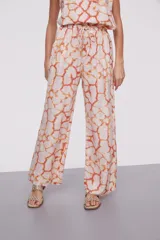 Pantalón palazzo de viscosa con estampado abstracto en tonos naranja, amarillo y blanco. Tiene cintura alta con cordón ajustable.